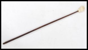An early 20th century bone and hardwood backscratcher in the form of a hand.