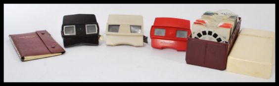 A group of vintage Viewmasters and discs to include three viewers in red brown and fawn, an album,