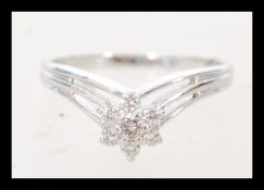 An 18 carat white gold ring featuring 6 diamonds set around a central stone and a double shank
