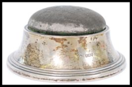 A hallmarked silver William Comyns & Sons pincushion of sloped circular form having a removable