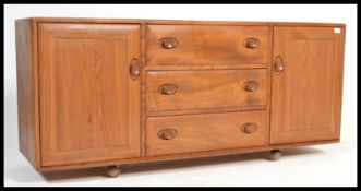 A 20th century light elm and beech wood sideboard by Ercol with three central drawers, the top