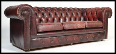 A 20th century antique style oxblood red leather Chesterfield sofa settee having buttoned back
