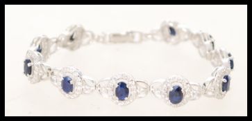 A silver Cubic Zirconia and sapphire paneled bracelet. The sapphires are set in prong settings