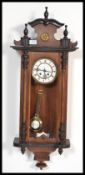 A vintage 20th century Vienna Regulator style mahogany cased wall clock having an arched pediment