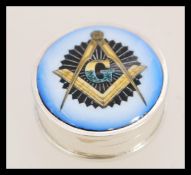 A contemporary silver pill box with an enamel panel featuring a Masonic ecclesiastical design