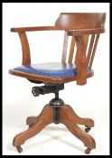 A vintage early 20th century Industrial oak office chair raised on a quadruped swivel base having