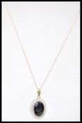 A 9ct gold white and blue stone pendant necklace having a central faceted blue stone with a halo