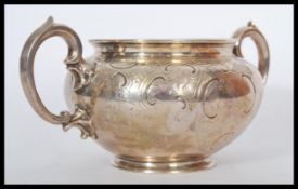 A hallmarked mid 19th century silver twin handled bowl having embossed scrollwork with scrolled