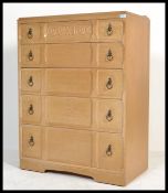 A 1950's light oak post war Art Deco chest of drawers having a central bank of 5 drawers with drop