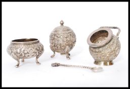 A set of three Persian Indian silver condiments cruets having embossed scroll work and flower head