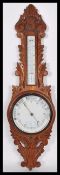 An early 20th century - 1930's milk glass facia oak wall barometer of banjo form having