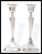 A matched pair of silver hallmarked candlesticks raised on square bases with tapering columns and