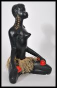 A vintage 20th century carved ebony figurine of a nude African lady in tribal attire on her knees