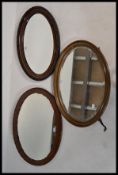 A group of three vintage early 20th century and later mirrors of oval form, set to carved oak and