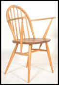 A mid century Ercol beech and elm carver armchair in the Windsor pattern. The shaped elbow rests