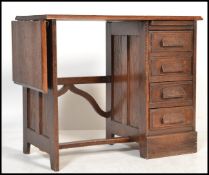 A 1920's oak childs / clerks desk having an open kneehole recess with bank of drawers and drop