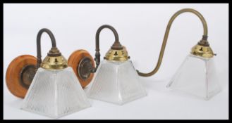 A set of three early 20th century brass wall light fixtures having square conical glass shades