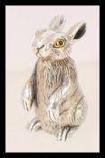 A contemporary sterling silver rabbit figurine featuring glass eyes.