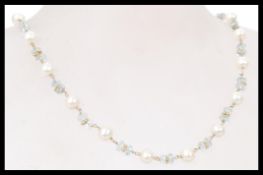 A necklace of pearls and aquamarine stones with 14 carat gold. The necklace is 14 inches in length