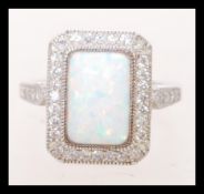 A contemporary silver ring with a large opal panel surrounded by Cubic Zirconia. It includes inset