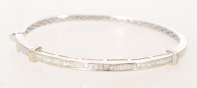 An 18ct white gold bangle bracelet with channel inset diamonds and a hidden clasp.