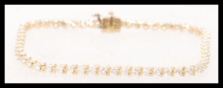 A 14 carat yellow gold diamond tennis bracelet with 2.3 CT diamonds. It features a bracelet catch
