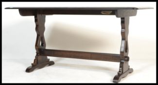 A 20th century Ercol beech and elm wood refectory dining table being raised on shaped supports