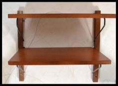 A retro 20th Century teak wood modular wall shelving system, three shelves supported with ebonised
