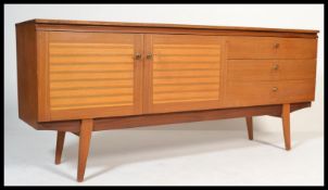 A 1970's teak wood sideboard credenza being raised on tapering supports with a bank of drawers