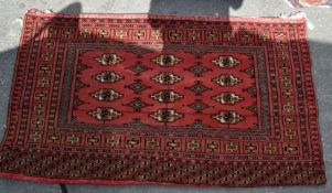 A 20th Persian Islamic century carpet floor rug with a red ground having a central panel with