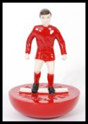 A Royal Doulton Subbuteo ceramic football figurine MCL 12 featuring a player in red kit on red base.