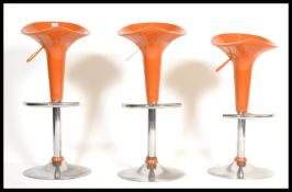 A set of 3 contemporary modernist gas bar stool in an orange colour way with chrome base and
