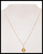 A hallmarked 9ct gold pendant necklace strung with a clam shell pendant with inset pearl. Hallmarked