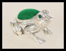 A vintage 20th century sterling silver frog pin cushion with inset emerald eyes.