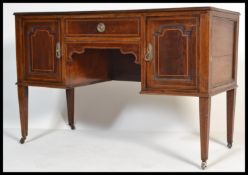 An  Edwardian inlaid mahogany kneehole writing table desk raised on tapering legs with brass castors