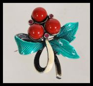 An enamel set brooch in the form of a holly leaf having a hinge pin fastening.