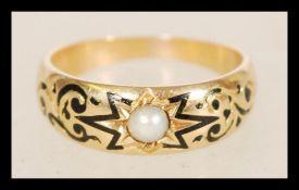 A 19th century Victorian 9ct gold ring set with a pearl having black enamel inlay within a