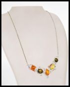 A vintage 20th century silver necklace having a scrolled collar with inset precious stones and amber