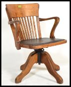 A vintage early 20th century Industrial oak office chair raised on a quadruped swivel base having