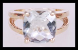 A contemporary 9ct gold ring with a split shank and inset blue stone in prong settings, hallmarked