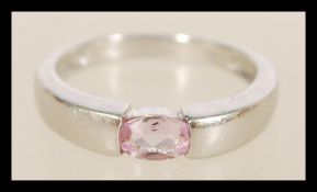 A hallmarked white gold band ring with inset flush pink stone weighing 3.6 grams hallmarked