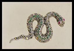 A silver 20th century brooch in the form of a snake with inset marcasites and emeralds and red
