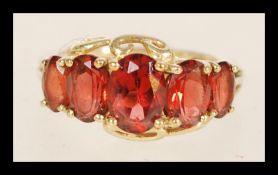 A 9ct hallmarked Birmingham gold contemporary ladies ring with 5 brown inset stones and scrolling