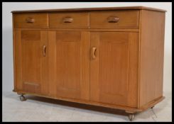 A 20th century blond sideboard by Priory furniture in the manner of Ercol with a configuration of