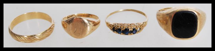 A group of four 9ct gold rings to include a black onyx signet ring, a five blue stone ring, a