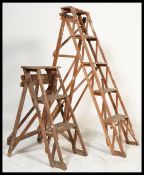 Two vintage 20th Century lattice Industrial framed wooden step ladders of differing sizes, the