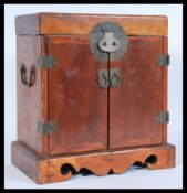 An early 20th century Chinese hardwood cabinet having lift up top with twin cupboard doors and brass