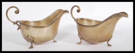 An early 20th century pair of Sheffield silver jugs by Walker & Hall having been set onto three cast