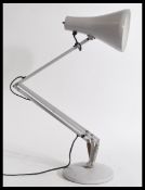 A 20th century vintage retro industrial style angle poise lamp with a lilac pendant shade on a
