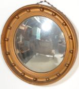 A Regency style gilt circular convex wall mirror, the frame finished in gilt with ball finial